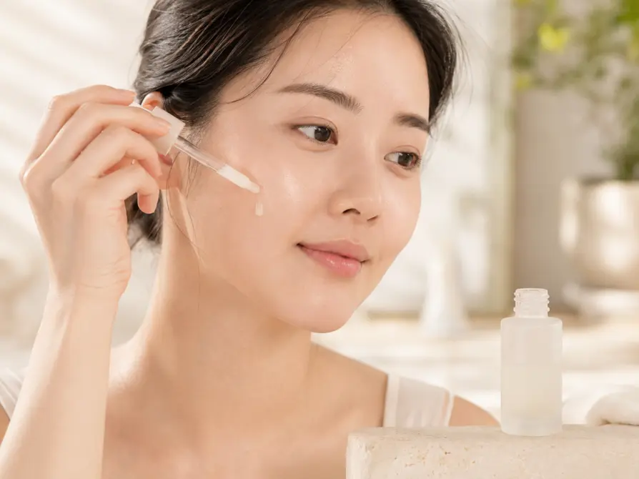 Kobieta nakładająca serum z kwasem mlekowym na policzek – delikatna pielęgnacja skóry wrażliwej.